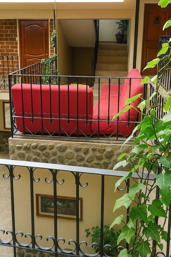 A red outdoor seating area with a stone wall and metal railing.