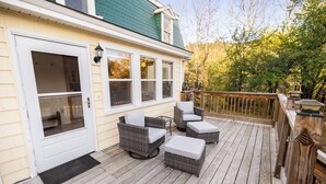 Eine Holzterrasse mit Korbmöbeln und einer Tür.