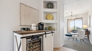 Una cocina con nevera para vinos, cafetera y adornos en estantes.