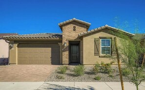 A single-story house with a garage, a small porch, and a landscaped front yard.
