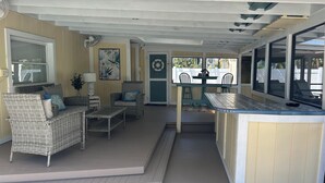 A covered outdoor area with wicker furniture, a small table, and a bar counter.