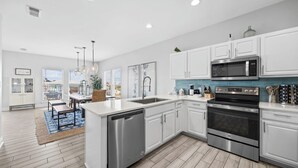 Una cocina moderna con armarios blancos, electrodomésticos de acero inoxidable y una isla grande con lavavajillas.