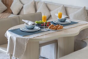 A breakfast setting with a table, plates, glasses, and a bowl of fruit.