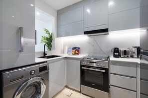 A modern kitchen with stainless steel appliances, a built-in washing machine, and a compact layout.