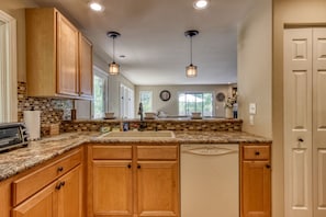 A kitchen with wooden cabinets, a granite countertop, a dishwasher, and pendant lighting. - Deer & Doe-Fire Pit-Private 3 Acres-2 Living Rooms (Sevierville)