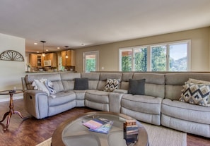 A living room with a sectional sofa, a glass coffee table, and a wooden side table. - Deer & Doe-Fire Pit-Private 3 Acres-2 Living Rooms (Sevierville)
