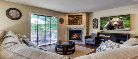 Una sala de estar acogedora con chimenea, asientos cómodos y un televisor grande con temática de osos.