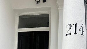 Una porta nera con maniglia in metallo e una colonna bianca con il numero 214.