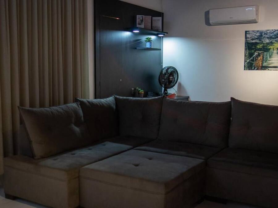 Una sala moderna con un sofá modular, un ventilador de pie y un aire acondicionado instalado en la pared.