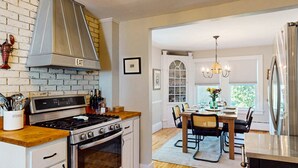 A kitchen with a stove, oven, and a dining area with a table and chairs. - Family-Friendly Boothbay Home, walk to Harbor (Boothbay Harbor)
