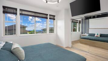 Un dormitorio moderno con una cama grande, un televisor instalado en la pared y vistas al exterior.