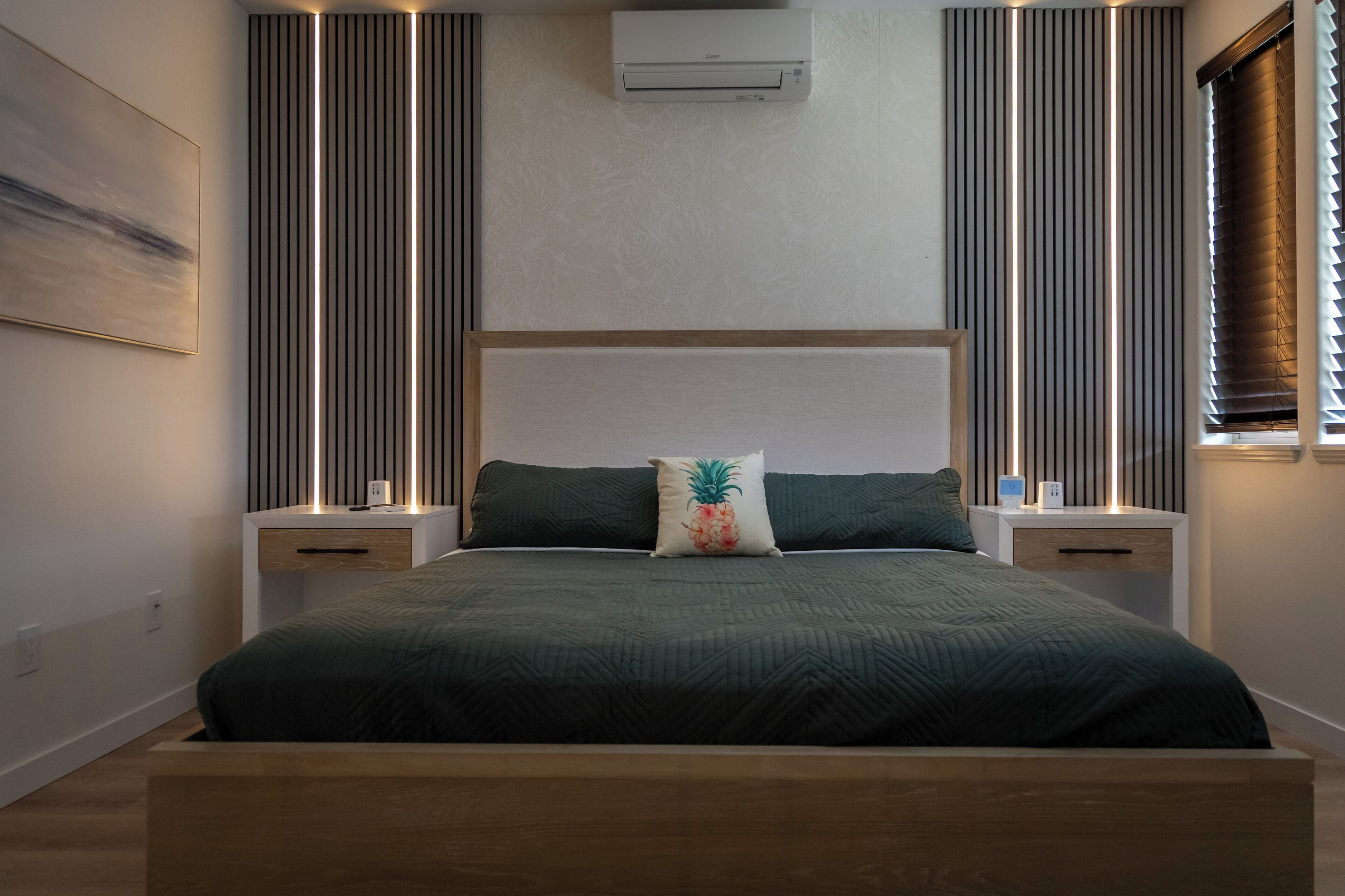 Una camera da letto moderna con un grande letto, due comodini, un condizionatore d'aria a parete e strisce luminose verticali.