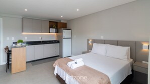 A modern hotel room with a bed, bedside tables, a desk, and a kitchenette. - Your Exclusive Stay in Blumenau, 350m From Vila Germanica - Ocns (Blumenau)