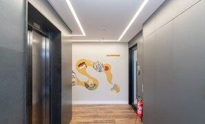 A modern hallway with a wooden floor, a fire extinguisher, and a welcome sign on the wall. - Your Exclusive Stay in Blumenau, 350m From Vila Germanica - Ocns (Blumenau)