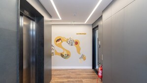A modern hallway with a wooden floor, a fire extinguisher, and a welcome sign on the wall. - Your Exclusive Stay in Blumenau, 350m From Vila Germanica - Ocns (Blumenau)