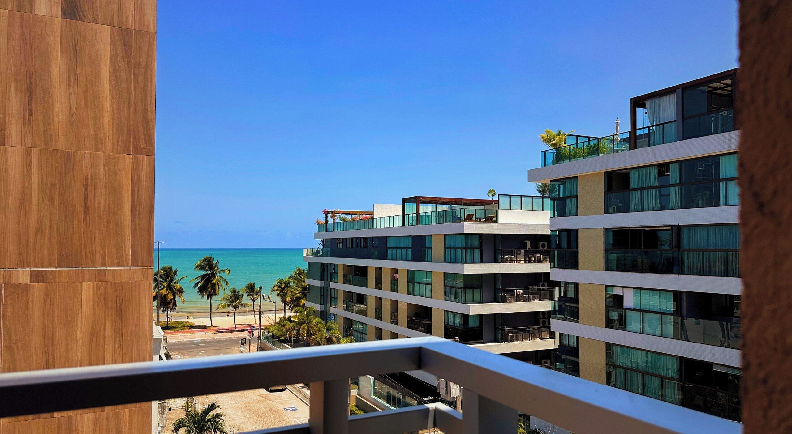 A multi-story hotel with balconies overlooking a beach and ocean.