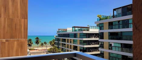 A multi-story hotel with balconies overlooking a beach and ocean.