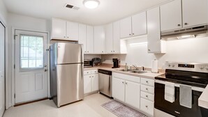 Una cocina moderna con armarios blancos, electrodomésticos de acero inoxidable y horno empotrado.
