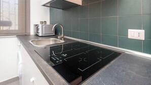 Et moderne køkken med en integreret induktionskogetop, en stålvask og en brødrister.