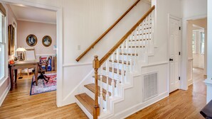 Un escalier avec des rampes blanches et des marches en bois menant à un palier.