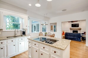 A spacious kitchen with white cabinetry, a central island with a stovetop, and a dining area with chairs.
