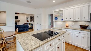 Une cuisine moderne avec des meubles blancs, un plan de travail en granit et une plaque de cuisson intégrée.