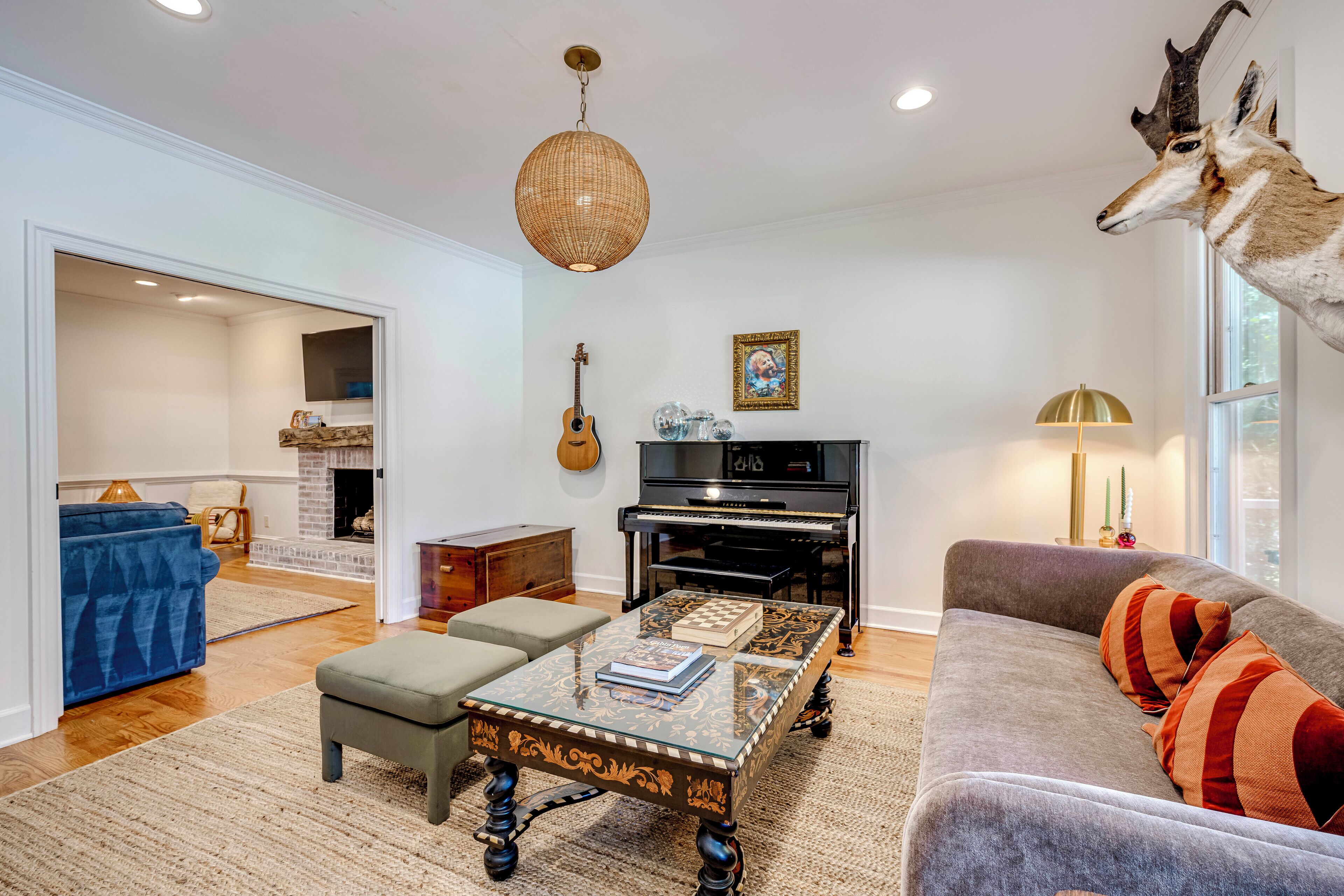 A living room with a piano, a sofa, a coffee table, and a mounted animal head.
