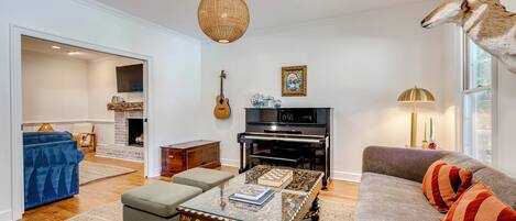 A living room with a piano, a sofa, a coffee table, and a mounted animal head.