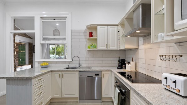 A modern kitchen with white cabinetry, a dishwasher, a stove, and a toaster.