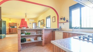A kitchen with a brick island, granite countertops, a gas stove, and a dishwasher. - Casa Rural Los Conde Guadalcanal by Ruralidays (Sevilla)