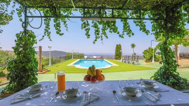 A table set for dining with a view of a pool and garden. - Casa Rural Los Conde Guadalcanal by Ruralidays (Sevilla)