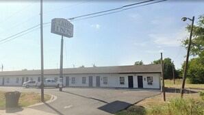A motel with a sign reading "CLASSIC INN" and a row of rooms with a simple, functional design. - Classic Inn Motel (Temple)