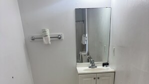 A small bathroom with a white sink, mirror, and cabinet. - Classic Inn Motel (Temple)
