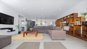 A modern living room with a sectional sofa, a coffee table, and a bookshelf.