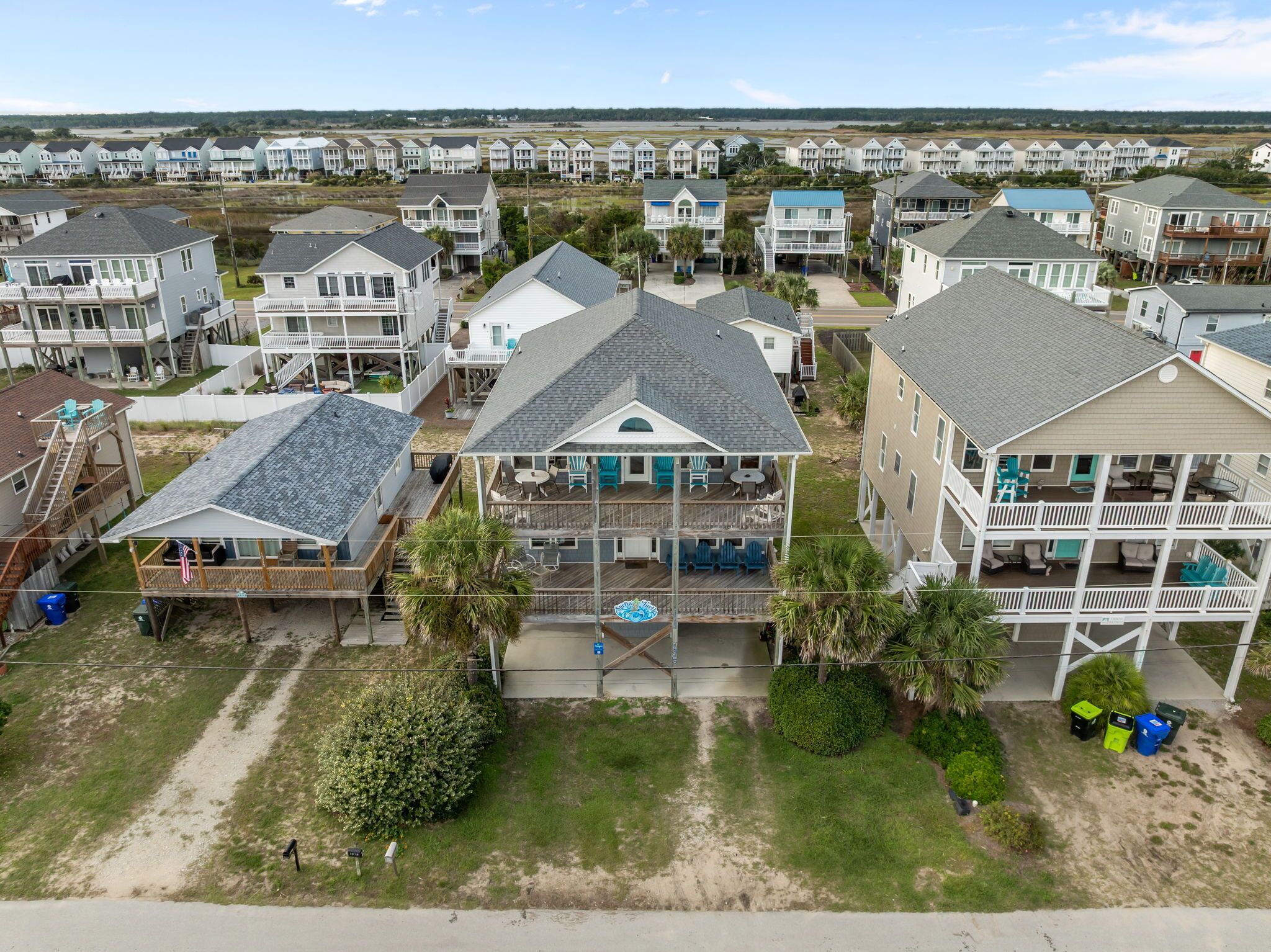 A coastal residential area with multi-story houses featuring balconies, a central courtyard, and a view of the beach.