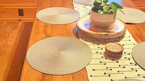 Een houten eettafel met placemats, een potplant en een schaal eten.