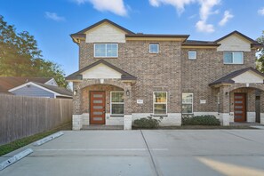 A two-story residential building with a brick facade, two front doors, and a small porch area.