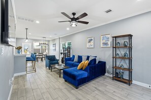 A modern living room with a blue sofa, a coffee table, and a ceiling fan.