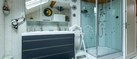 Een moderne badkamer met een douchecabine van glas, een donkerblauwe wastafel en een witte wasbak.