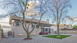 Une maison moderne avec une façade en briques, un patio couvert agrémenté de mobilier d’extérieur et une pelouse bien entretenue.
