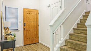 Un escalier avec des marches en bois et des rampes blanches menant à une porte.