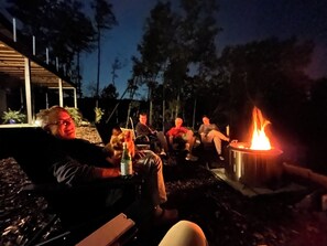 Eine Gruppe von Menschen sitzt an einem Lagerfeuer im Freien.
