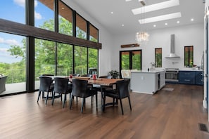 Eine moderne Küche mit Essbereich, großen Fenstern und Blick ins Freie.
