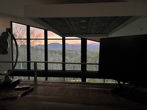 Ein Zimmer mit großen Fenstern und Blick auf Berge und Bäume.