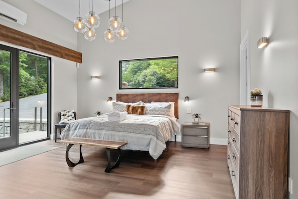 Ein modernes Schlafzimmer mit einem großen Bett, einer Bank, einem Nachttisch und einer Kommode.