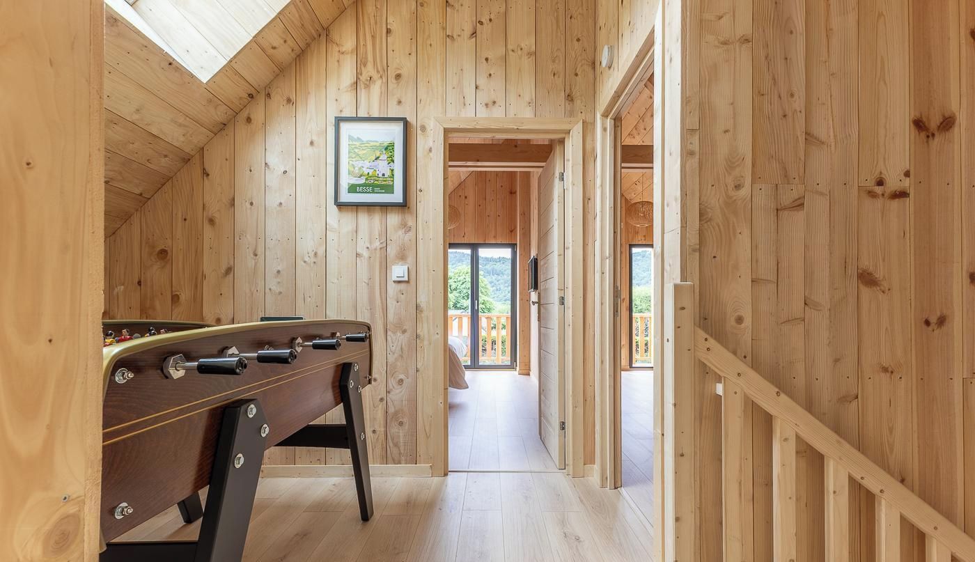 A wooden-floored corridor with a foosball table and a framed picture on the wall.