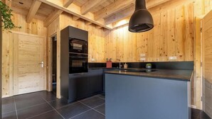 Eine moderne Küche mit Holzwänden, einem schwarzen Kühlschrank und einer zentralen Kochinsel.