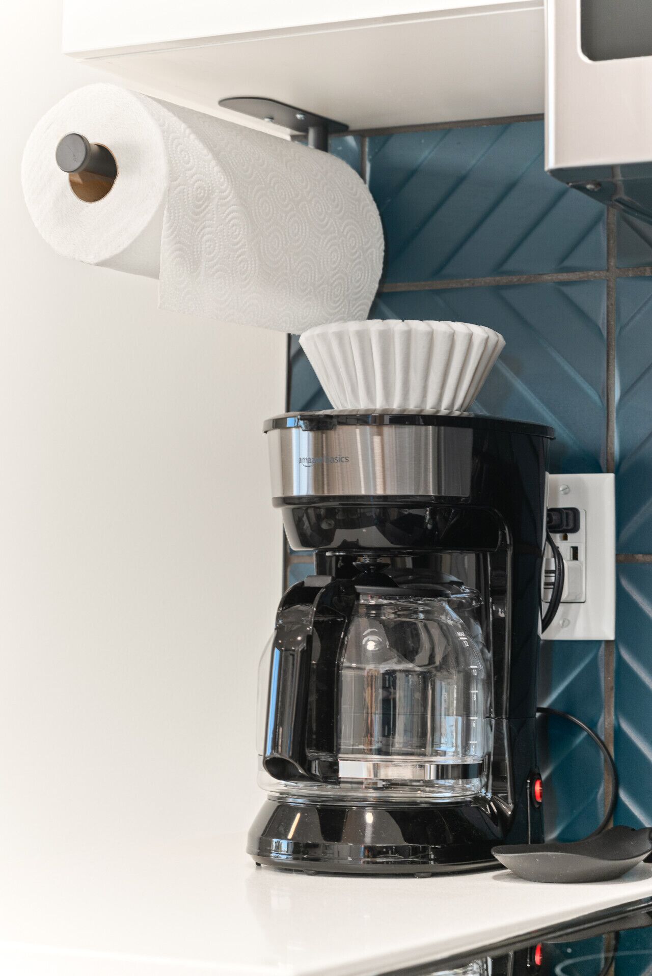 - Coffee maker setup with paper towels and easy access filters   - Perfect for morning brews before exploring the city   - Conveniently placed under cabinets for a clean workspace
