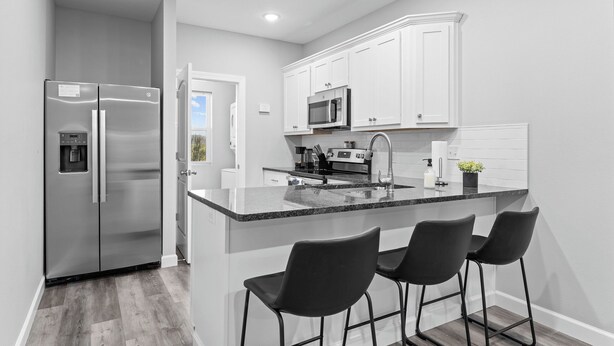 A modern kitchen with white cabinets, stainless steel appliances, a granite countertop, and black bar stools. - No Steps! Peaceful, Picturesque & Quiet Location - 3 Bed 2 Bath Condo (Branson)