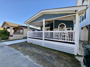 Kaksikerroksinen talo, jossa on katettu kuisti ja aidattu etupiha.